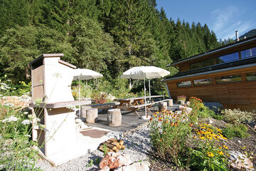 Blick auf die Terrasse und den gemauerten BBQ-Grill beim Alpin Chalet Classic in Filzmoos.