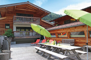 Die Terrasse mit Tischen und Sitzbänken beim Alpin Chalet Classic in Flachauwinkl.